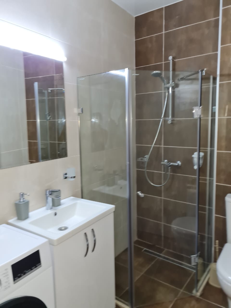 White Sails 6th floor apartment bathroom glass shower enclosure washing machine vanity brown tile